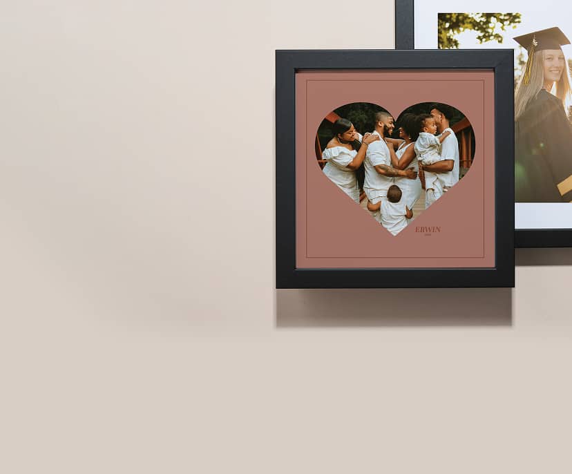 two stacked black framed pictures. One picture features a family photo within a heart-shaped mask.